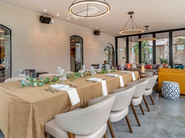 A dining area with a long table set for a meal, chairs, and modern light fixtures.