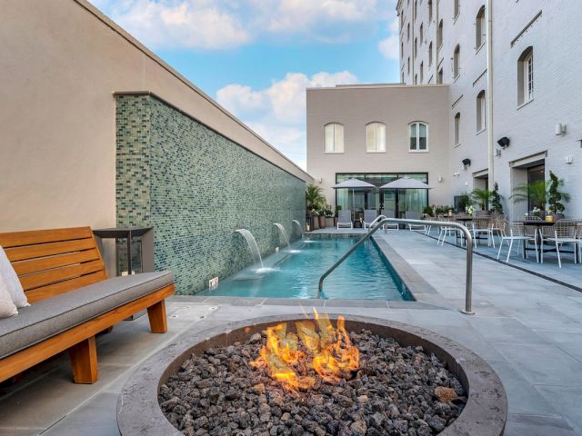 A pool area with a fire pit, outdoor seating, and a waterfall feature.