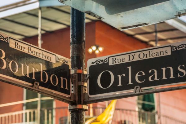 A street sign at the corner of Rue Bourbon and Rue D'Orléans in a vibrant area, with buildings in the background.