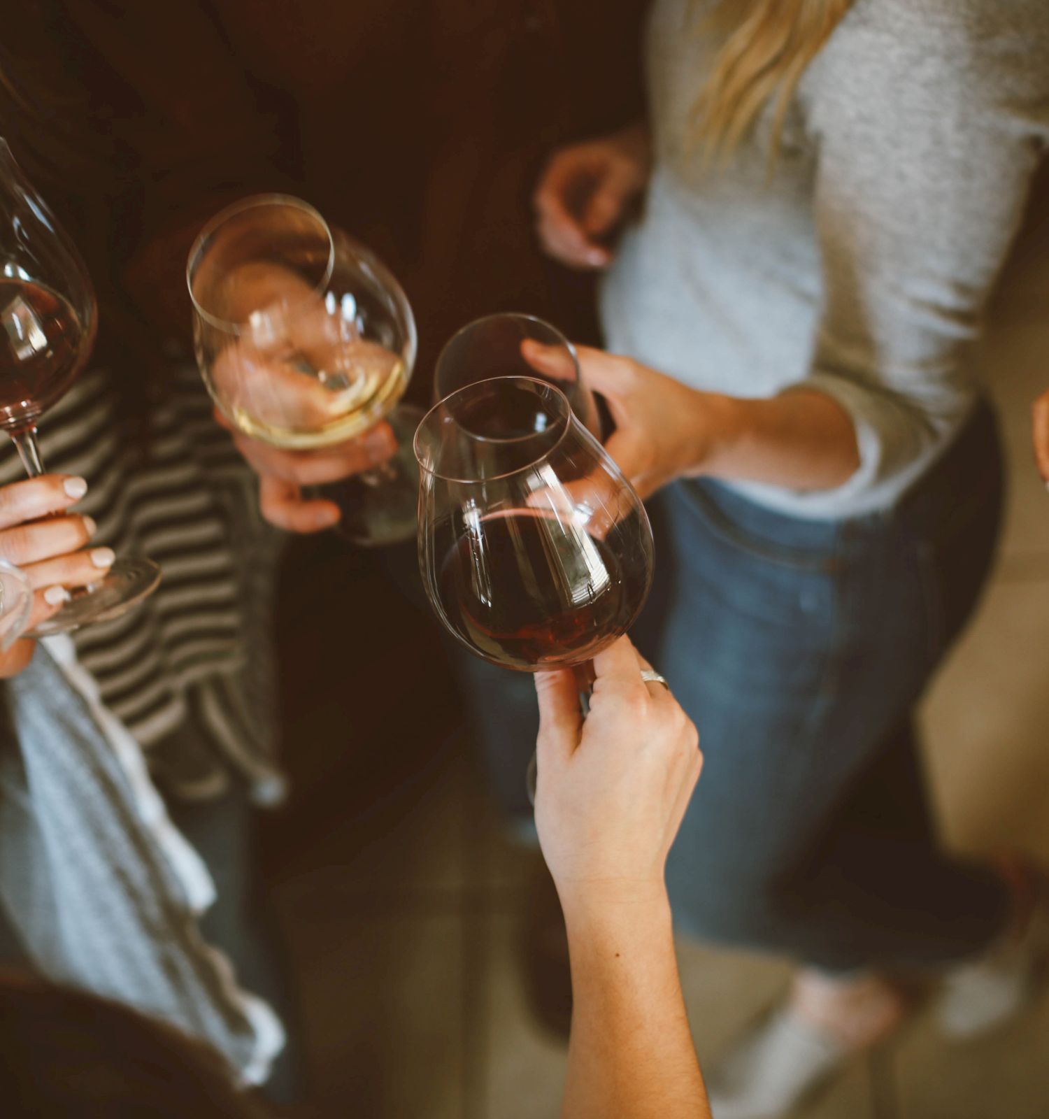 A group of people holding and toasting with glasses of red and white wine, seen from a top-down perspective. Ending the sentence.