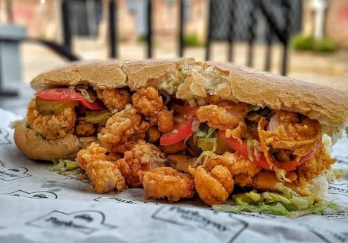 A crunchy fried-chicken sandwich with breaded bites, lettuce and tomato piled in a baguette, ready to eat.