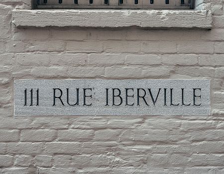 A brick wall with a gray stone plaque reading &ldquo;III RUE IBERVILLE&rdquo; mounted in the center.