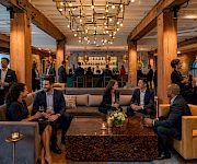 Friends in a modern bar lounge chat and toast with drinks under warm hanging lights.